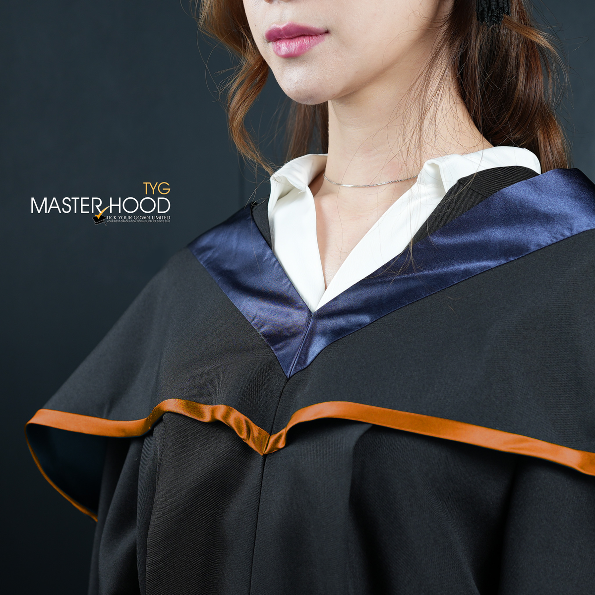 Profile view of a person wearing a black graduation gown and hood with an orange trim on a dark background