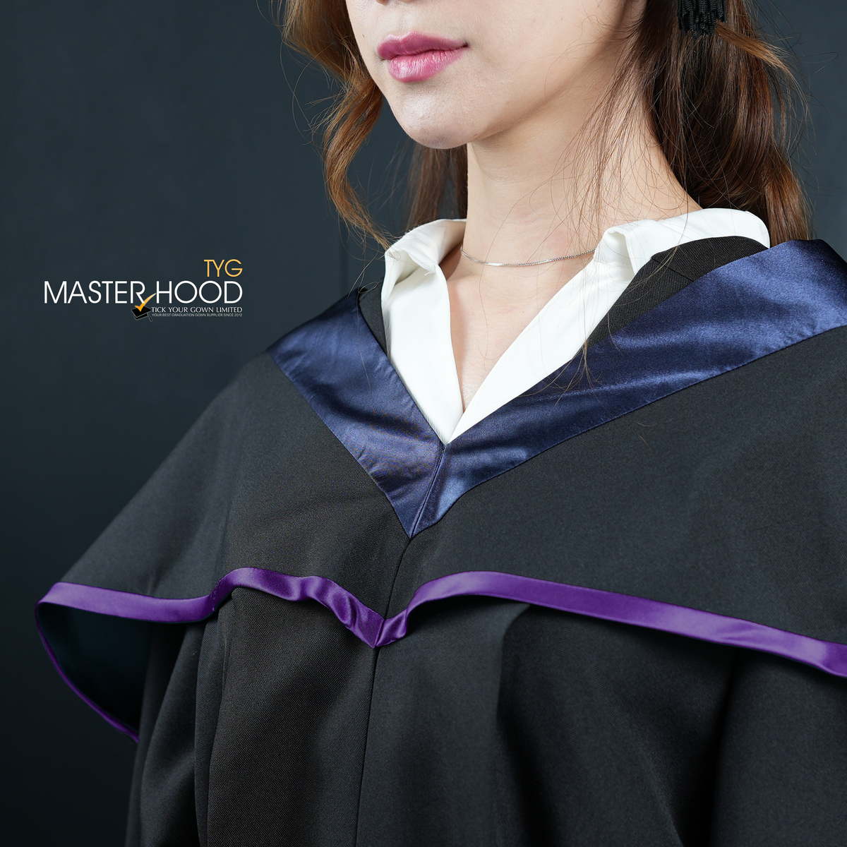 Profile view of a person wearing a black graduation gown and hood with a purple trim on a dark background