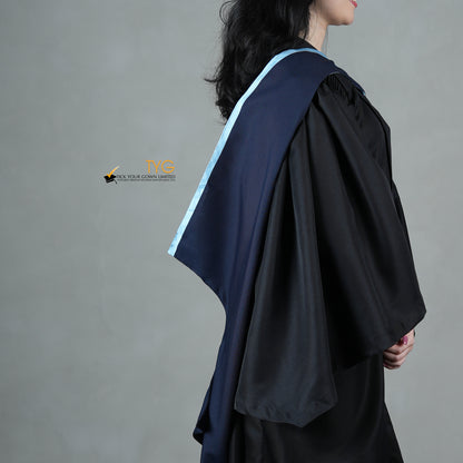 A profile side view of a graduate in a black gown with a navy blue hood with light blue lining against a gray background
