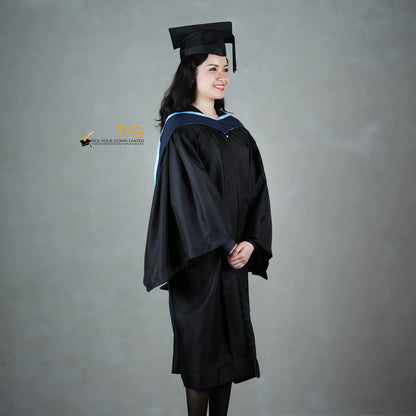 A profile view of a graduate in a black cap and gown with a navy blue hood with light blue lining against a gray background