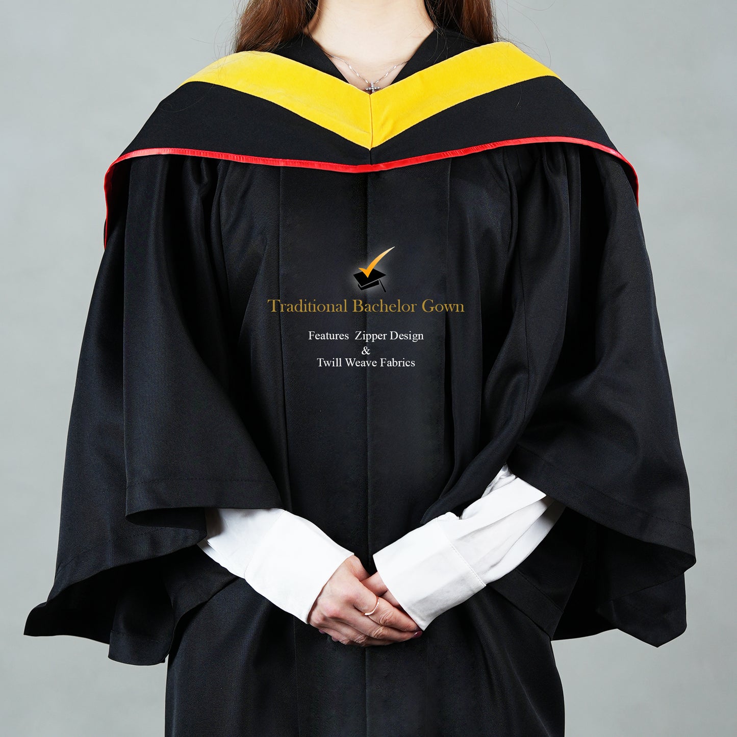 Front close-up of a black bachelor graduation gown showing the yellow and red-trim satin hood drape over the shoulders.