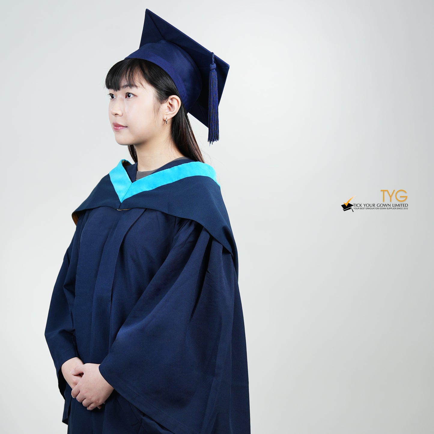 A detailed profile view of a person wearing a blue graduation gown and cap on a white background with 'TYG' logo.