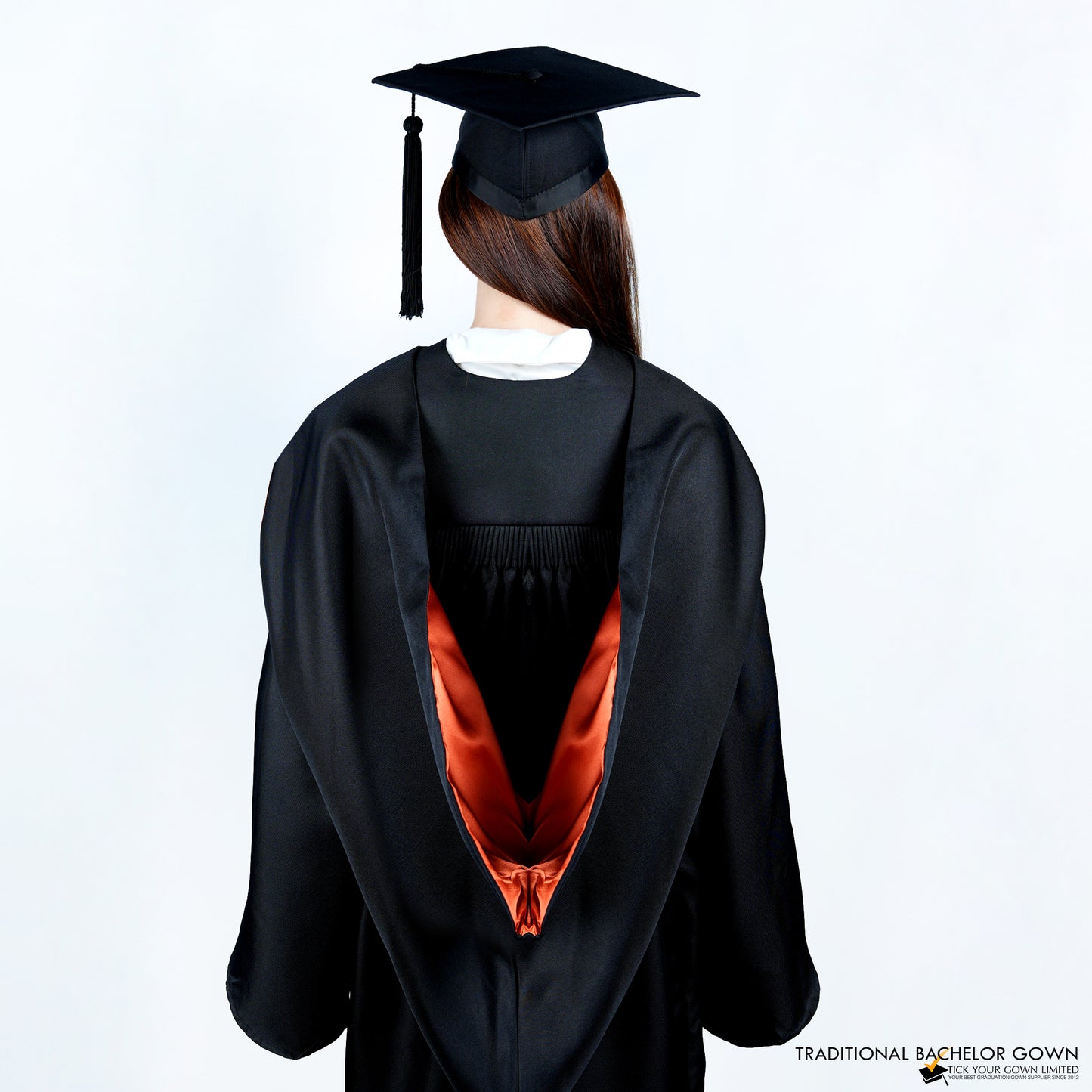 A person wearing a black bachelor graduation gown from the back with a colored inner satin hood, and a mortarboard