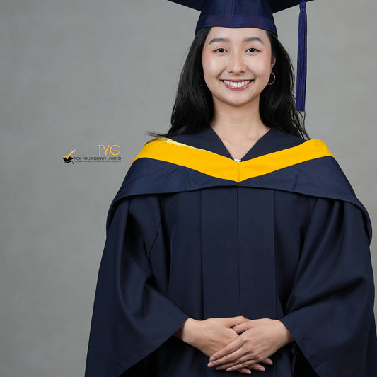 A detailed front view of a graduate in a navy cap and gown with a yellow hood against a gray background