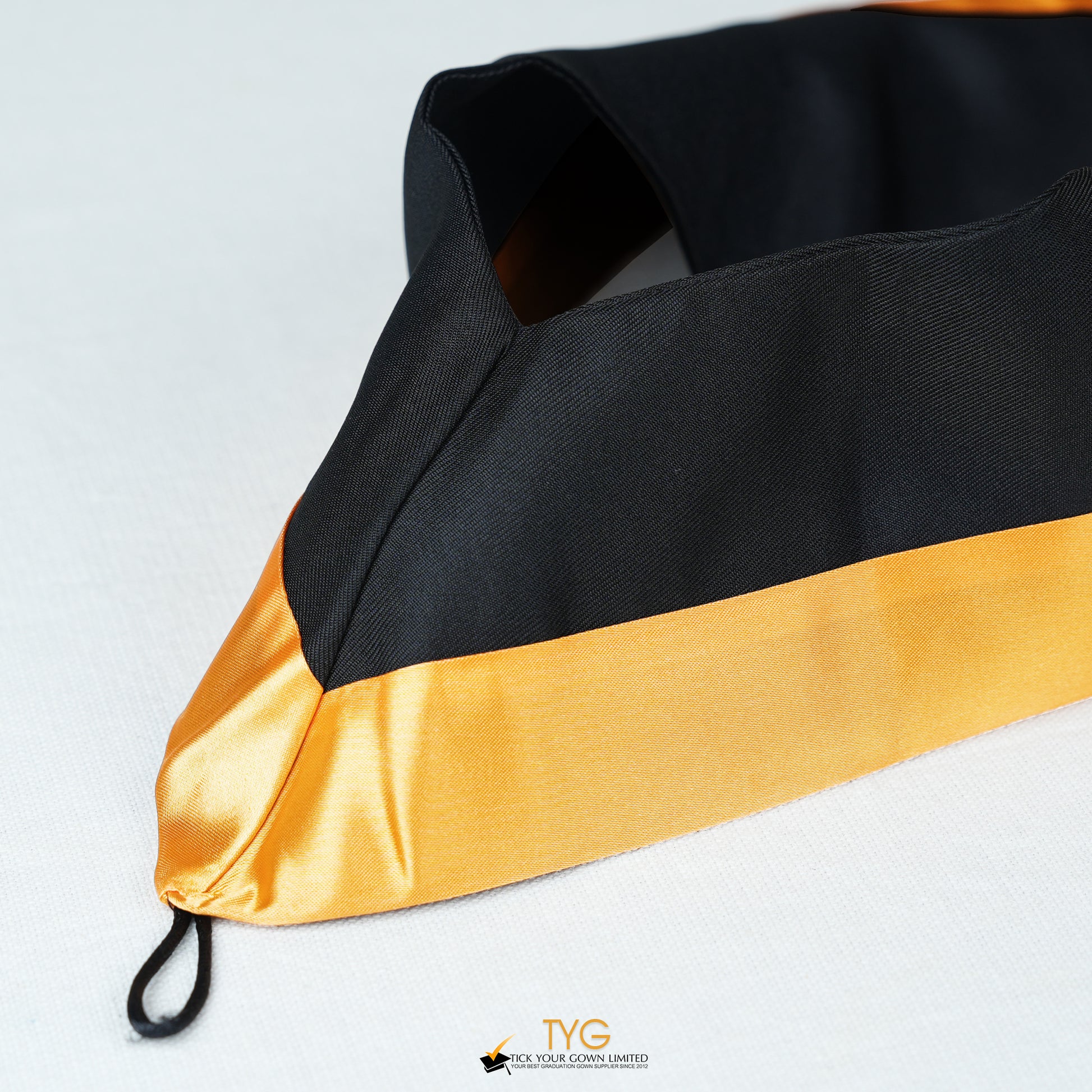 Detailed view of a bachelor’s graduation hood in black with gold satin lining.