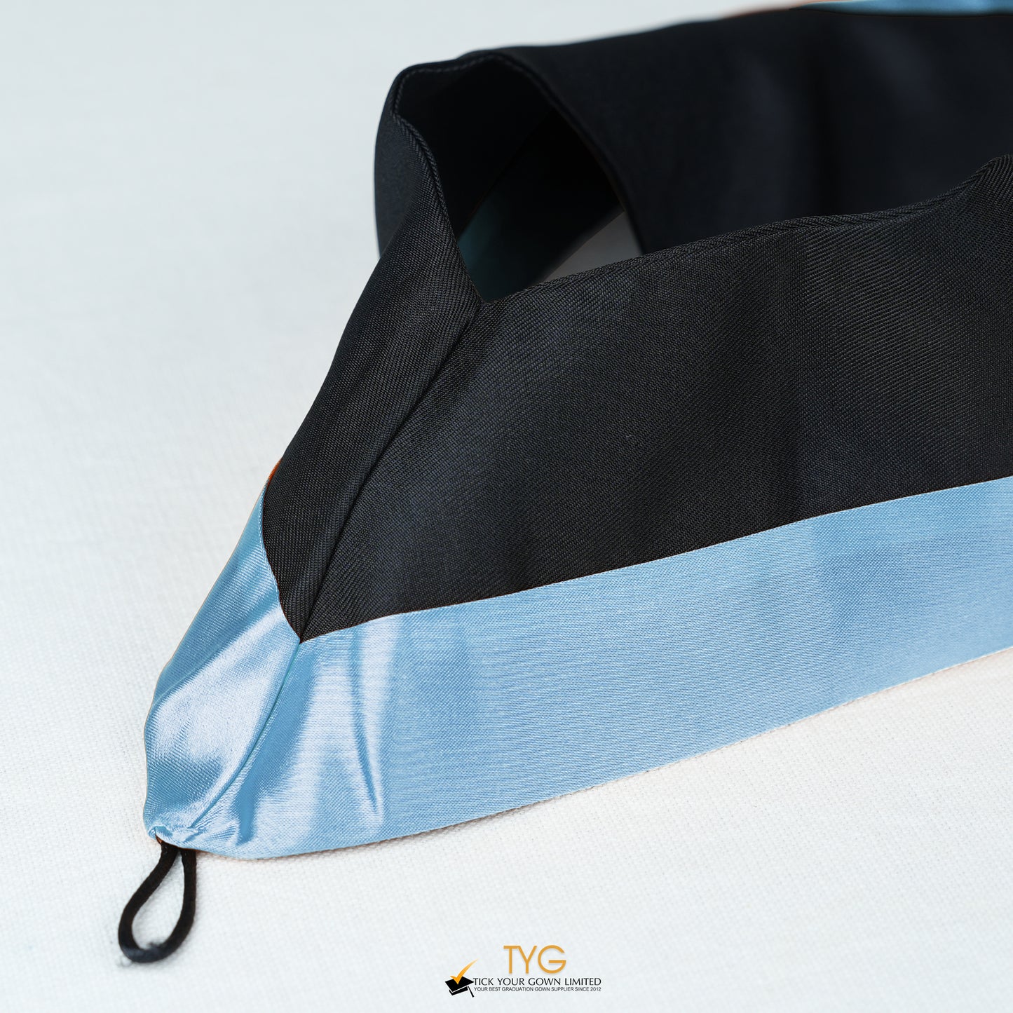Detailed view of a bachelor’s graduation hood in black with light blue satin lining.