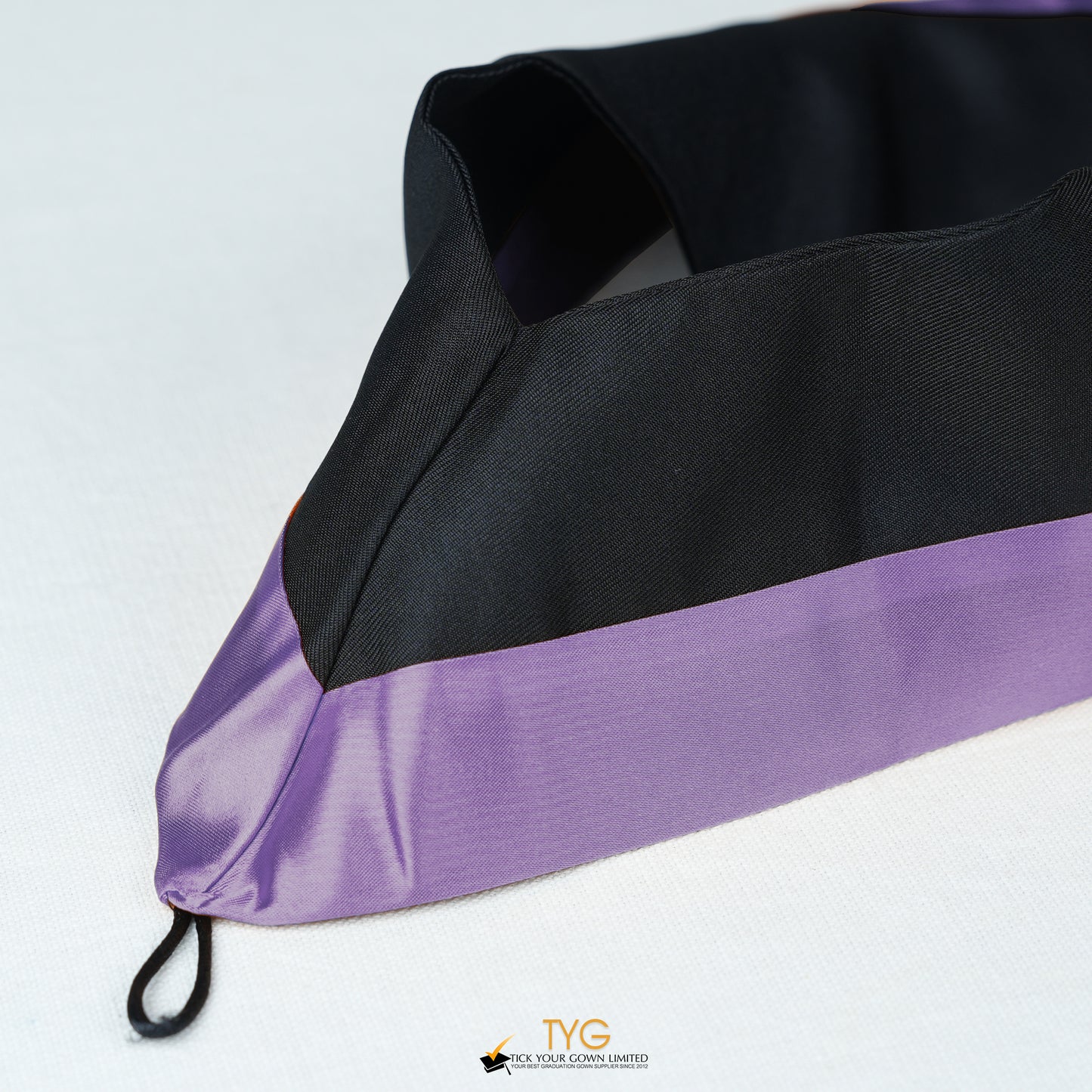 Detailed view of a bachelor’s graduation hood in black with purple satin lining.