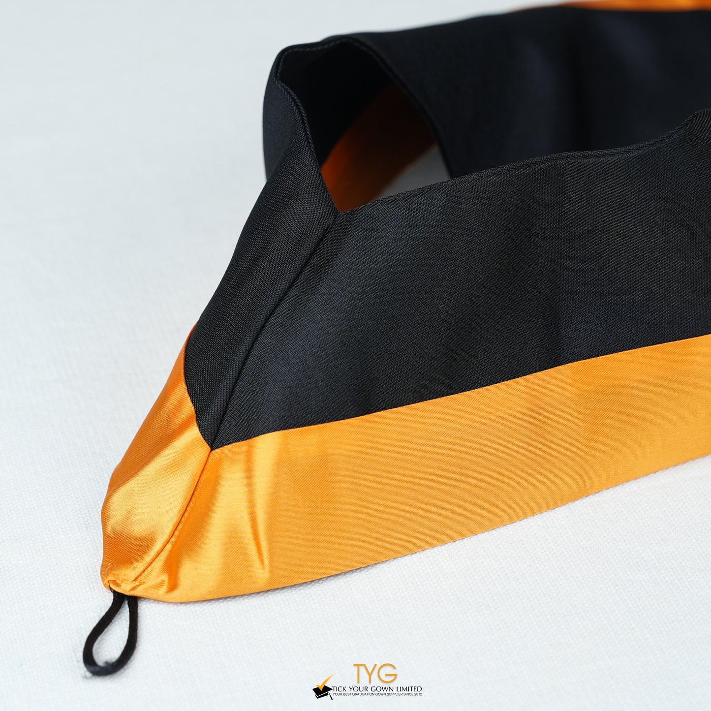 Detailed view of a bachelor’s graduation hood in black with orange satin lining.