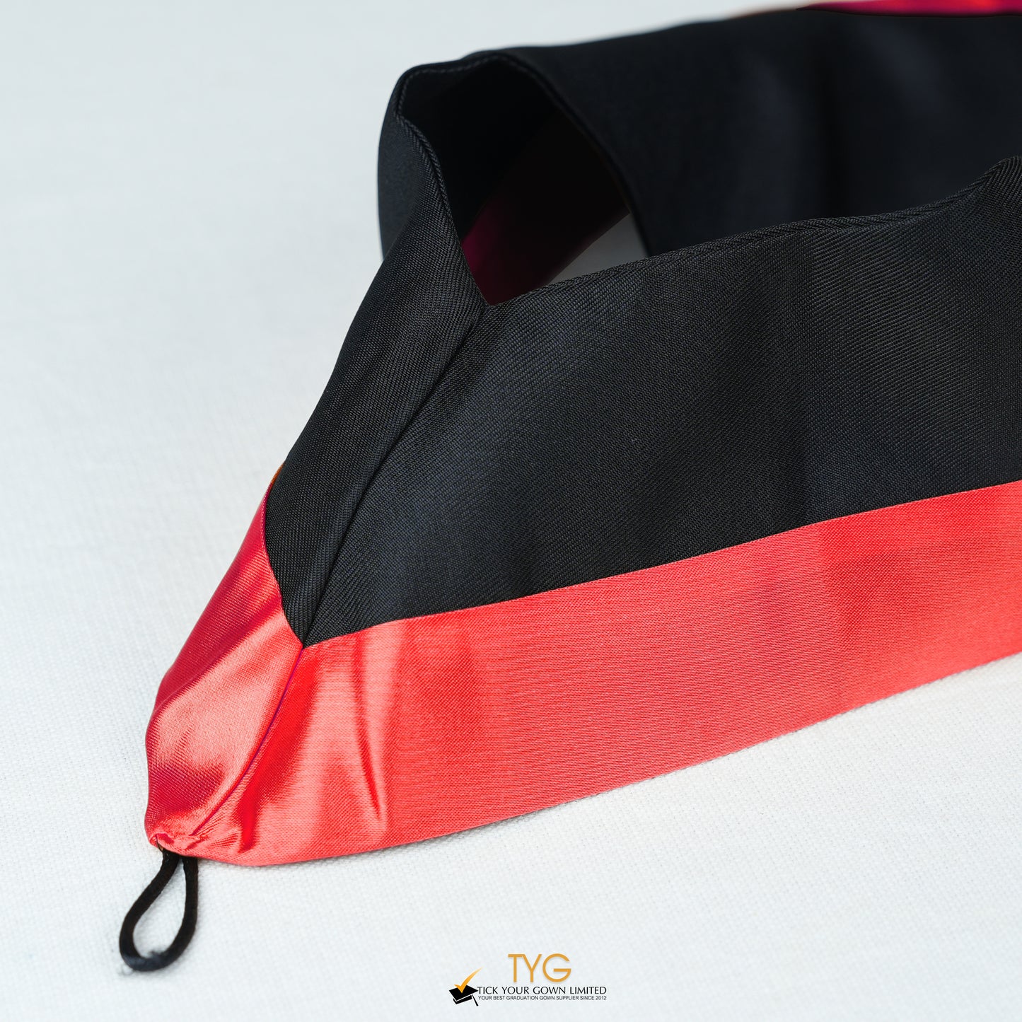 Detailed view of a bachelor’s graduation hood in black with red satin lining.