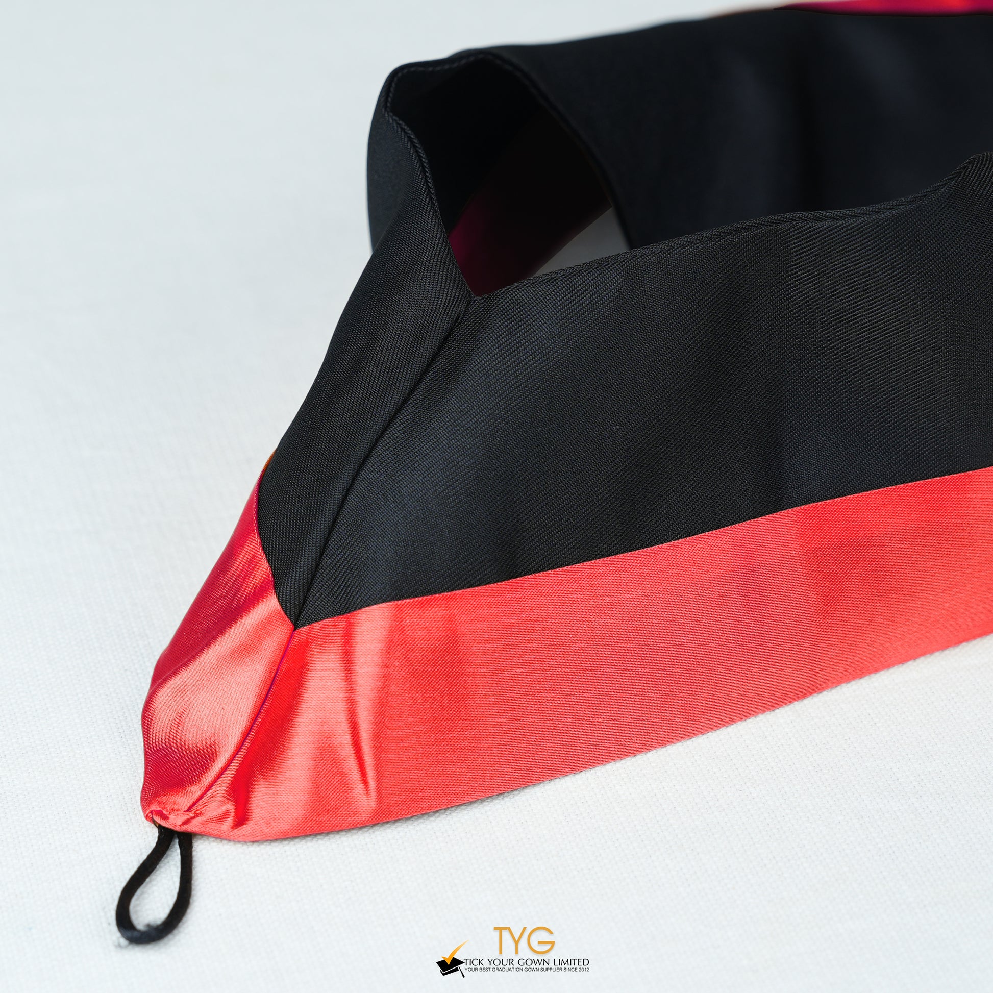 Detailed view of a bachelor’s graduation hood in black with red satin lining.