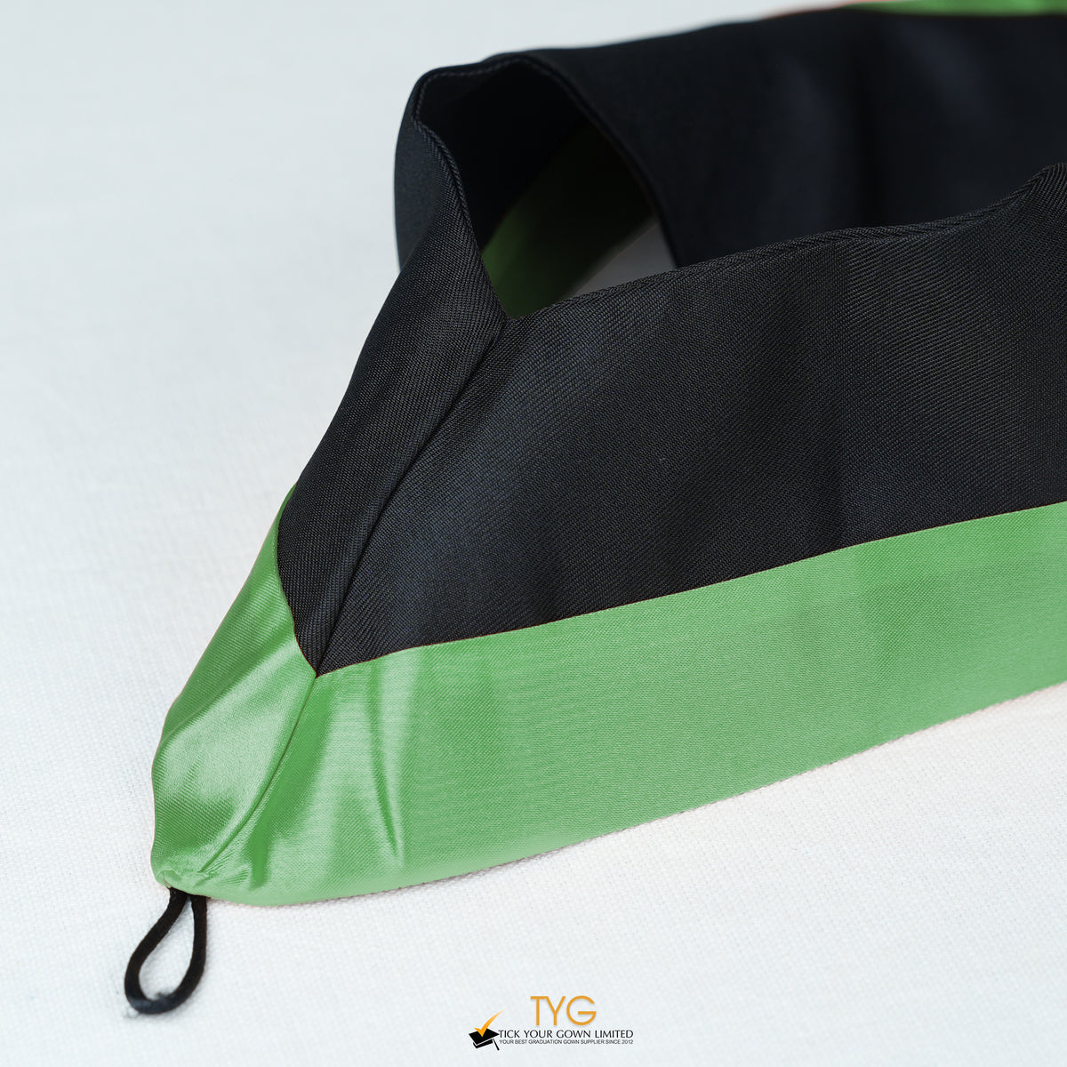 Detailed view of a bachelor’s hood in black with green satin lining.