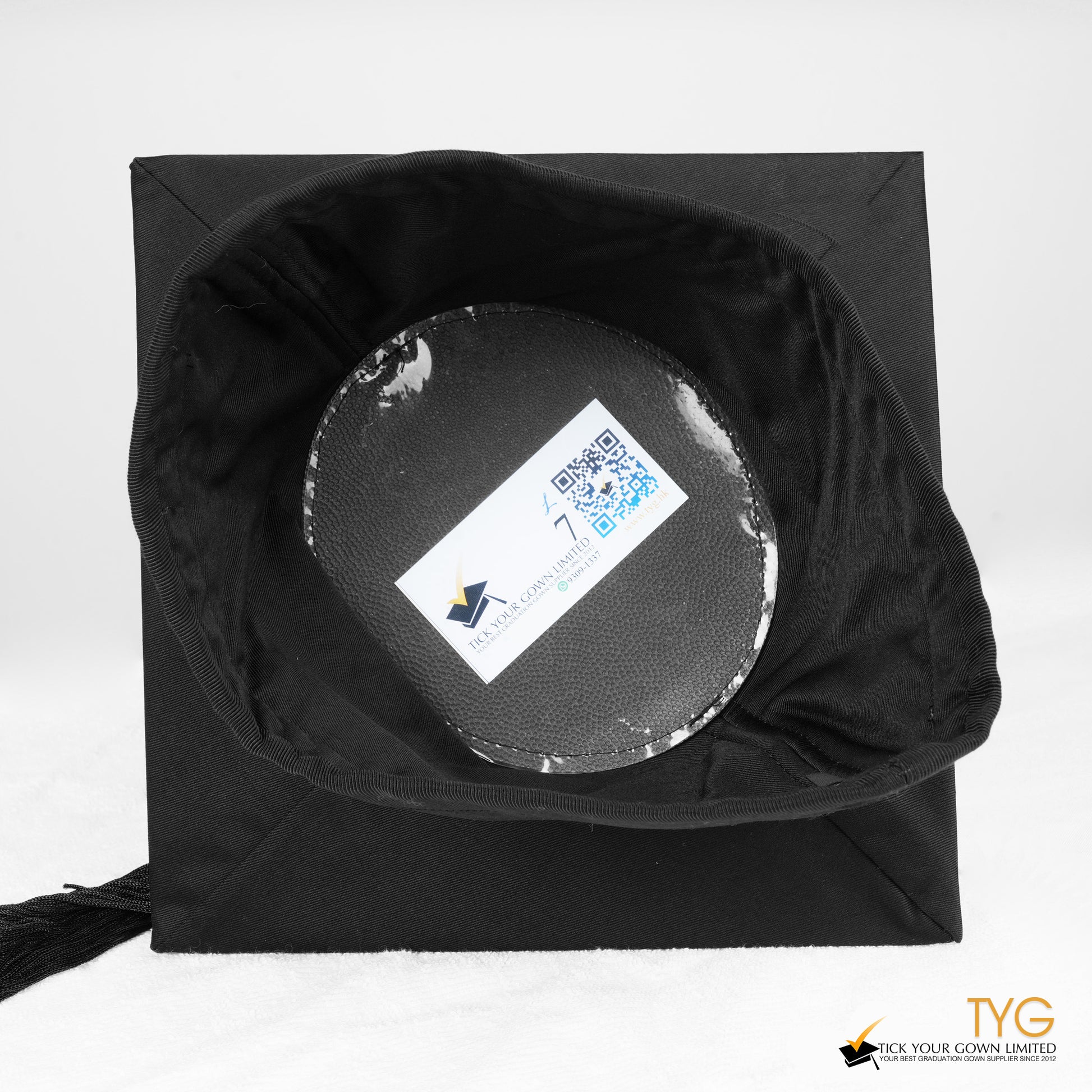 An inside view of a black graduation cap with a black tassel on a white background.