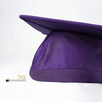 A detailed view of a purple graduation cap with a purple tassel on a white background.