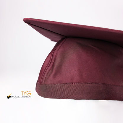 A detailed view of a red graduation cap with a red tassel on a white background.
