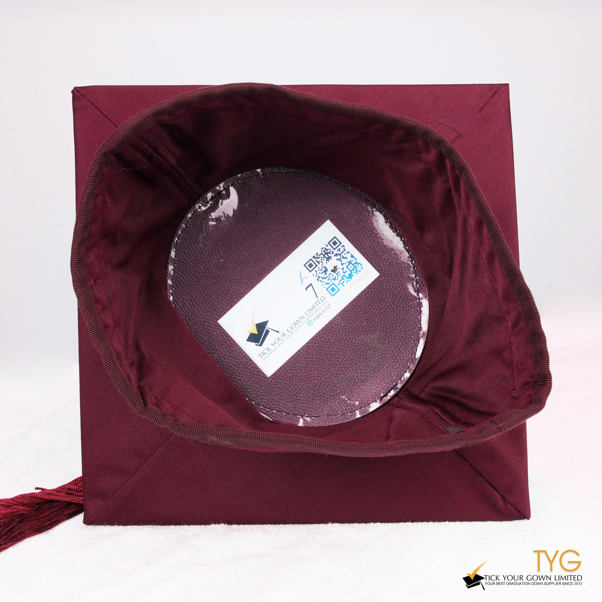 An inside view of a red graduation cap with a red tassel on a white background.