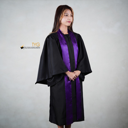 Profile view of a person wearing a black graduation gown with a purple graduation sash on a gray background