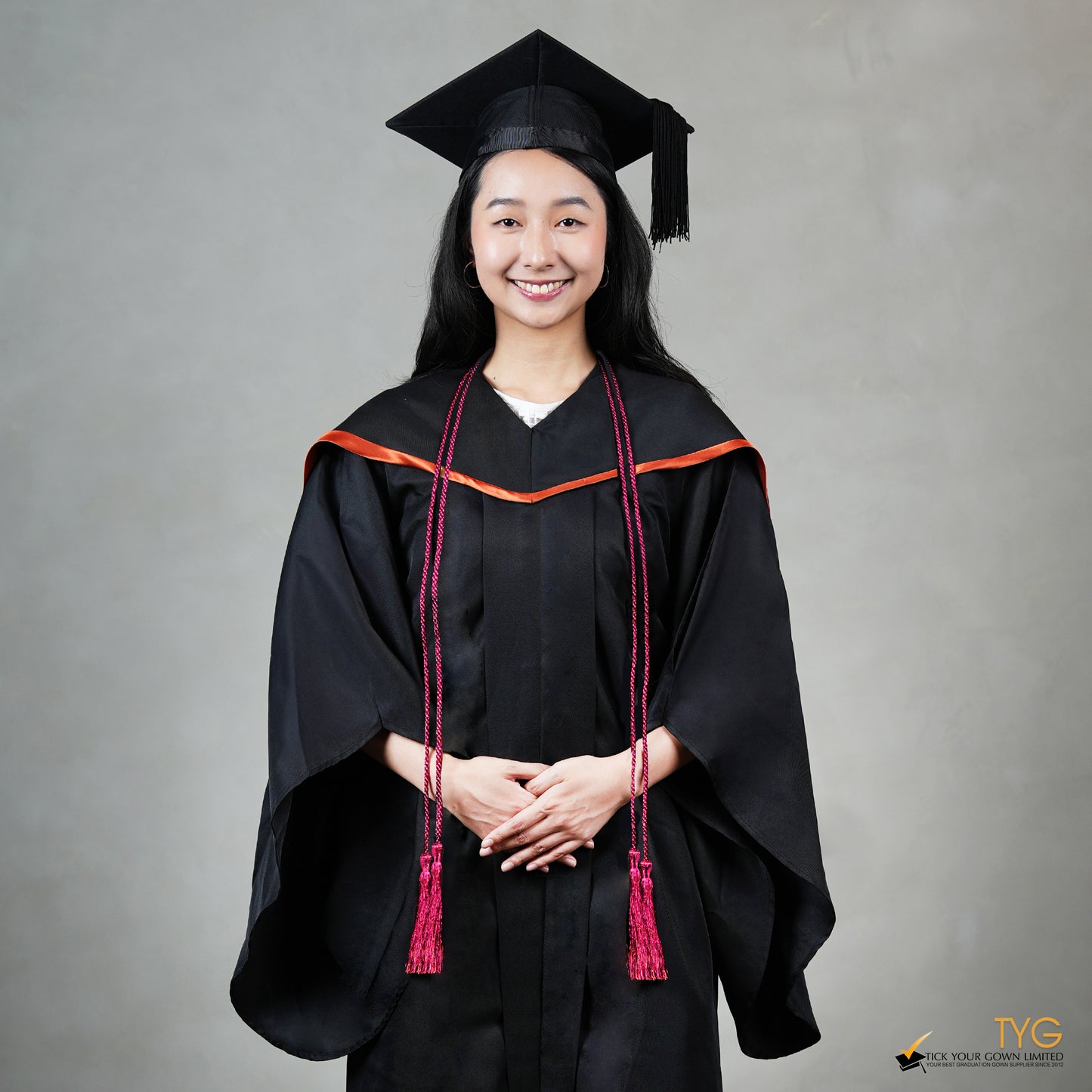 Graduate in black cap and gown with red honour cords on a gray background