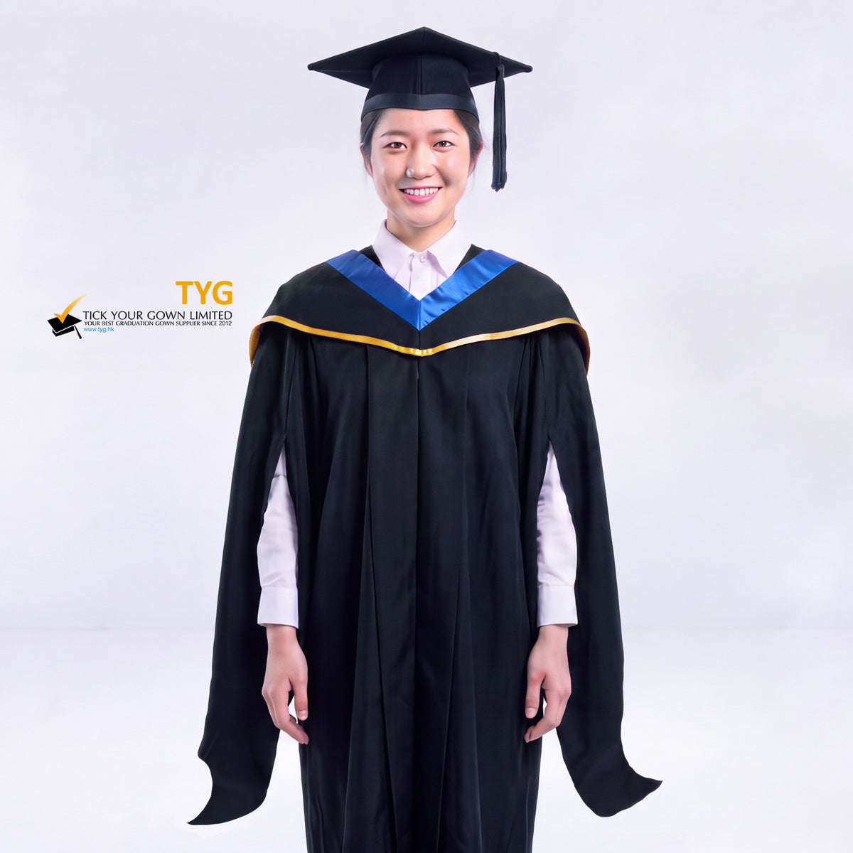 A woman in a black master's graduation gown classic UK with a blue hood with gold trim accent and with a black mortarboard cap with a black tassel against a gray background.