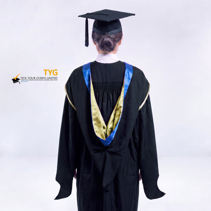 A back view of a woman in a black master's graduation gown classic UK with a blue hood with yellow trim accent and with a black mortarboard cap with a black tassel against a gray background.