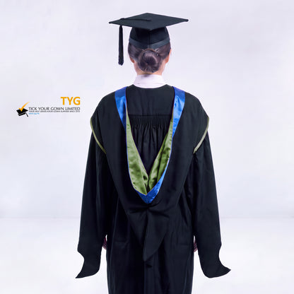 A back view of a woman in a black master's graduation gown classic UK with a blue hood with green trim accent and with a black mortarboard cap with a black tassel against a gray background.