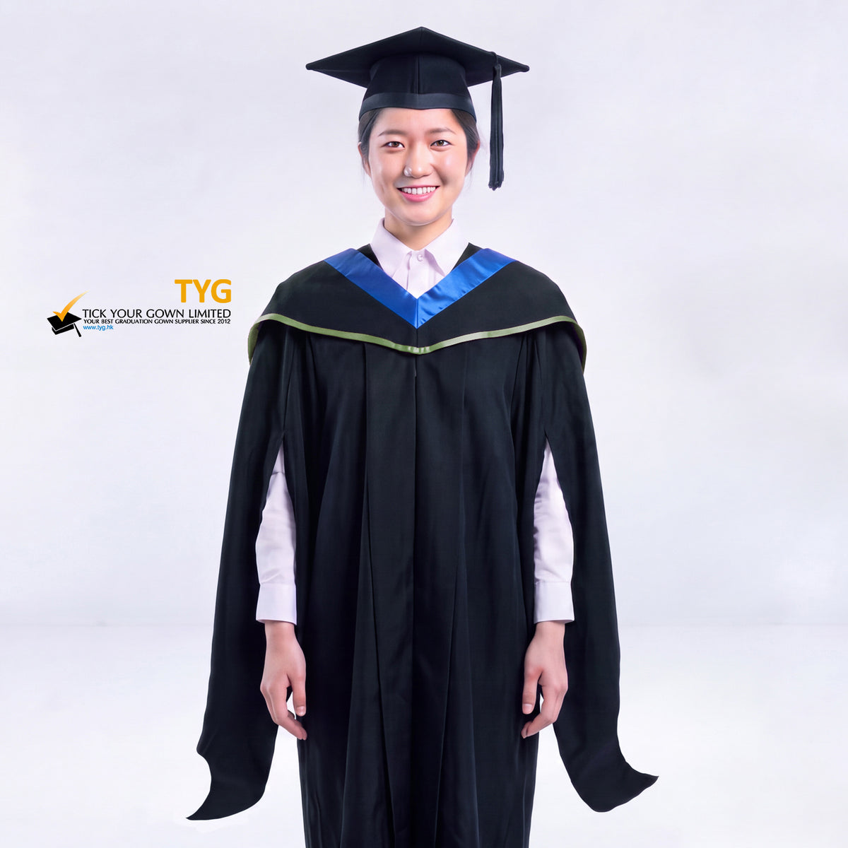 A woman in a black master's graduation gown classic UK with a blue hood with green accent and with a black mortarboard cap with an black tassel against a gray background.
