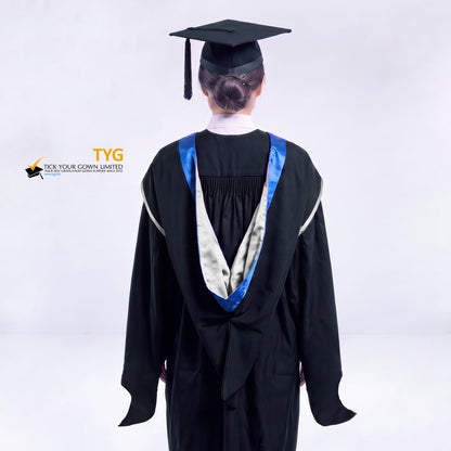 A back view of a woman in a black master's graduation gown classic UK with a blue hood with silver trim accent and with a black mortarboard cap with a black tassel against a gray background.