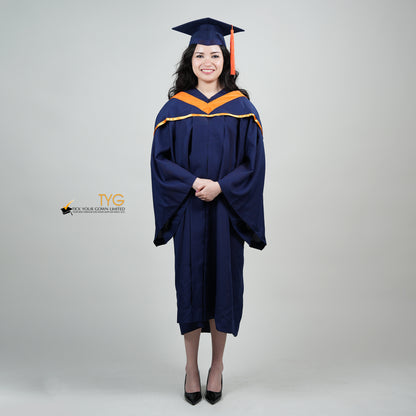 A full body shot of a person in a navy blue graduation gown and an orange hood and with a mortarboard cap with an orange tassel against a gray background.