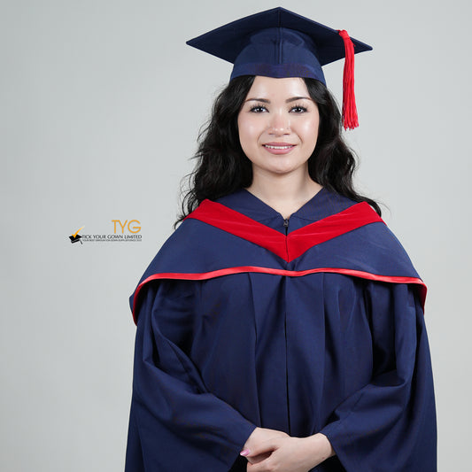 A person in a navy blue graduation gown and a red hood and with a mortarboard cap with a red tassel against a gray background.