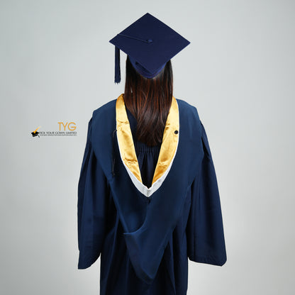A back view of a person in a navy blue graduation gown and a white hood with gold lining and with a mortarboard cap with a white tassel against a gray background.