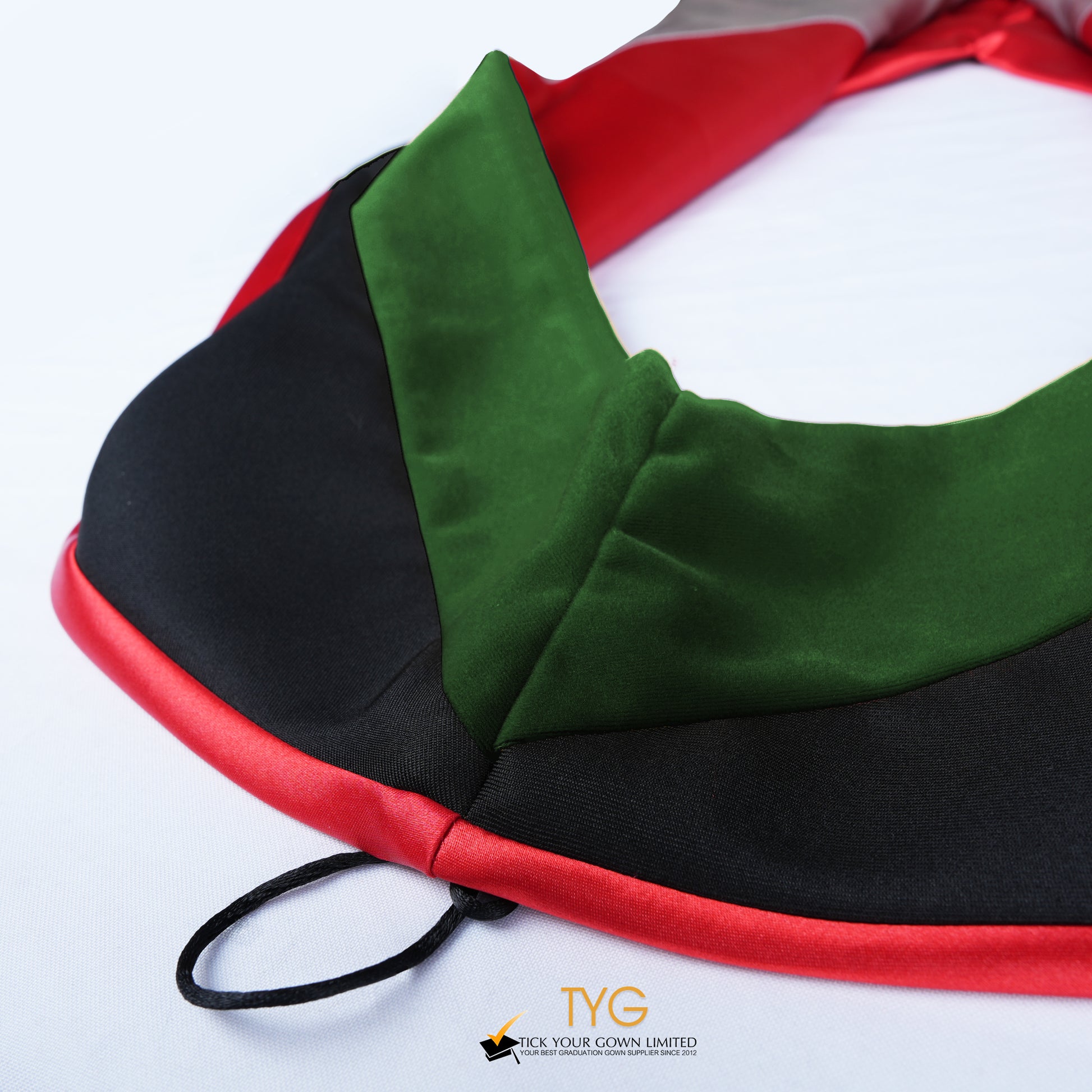 Close-up of a master's graduation hood featuring black fabric with forest green velvet hood and red satin lining.