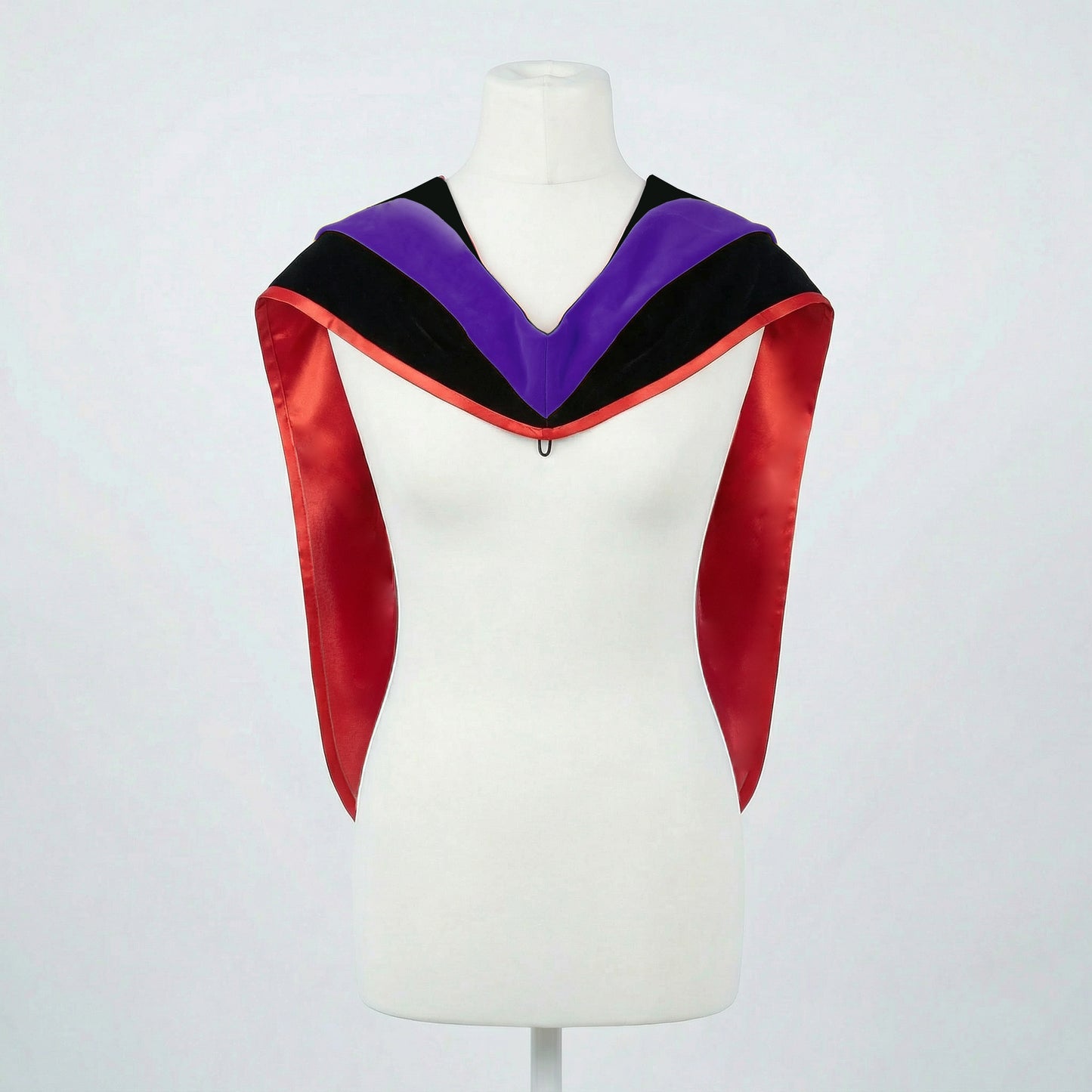 Master's graduation hood displayed on a mannequin showing full shape with black velvet body, purple velvet hood and red satin lining.