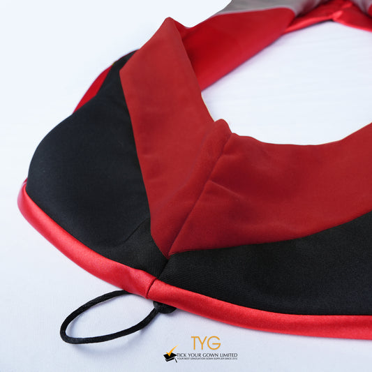 Close-up of a master's graduation hood featuring black fabric with red velvet hood and red satin lining.