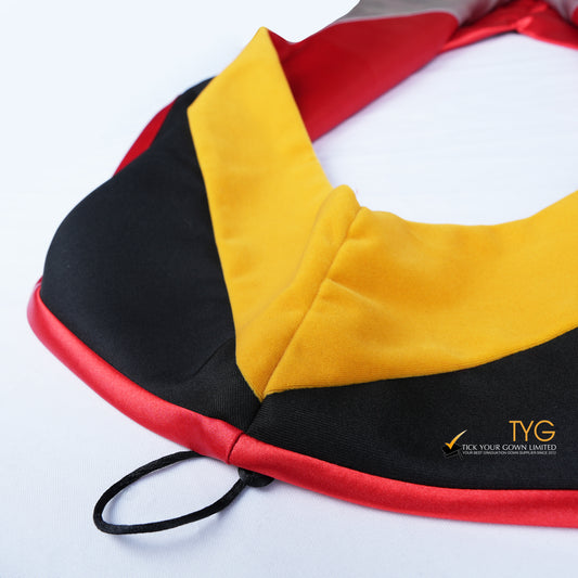Close-up of a master's graduation hood featuring black fabric with yellow velvet hood and red satin lining.