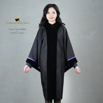 A person wearing a black Traditional Master's graduation gown with a front velvet panel, including satin velvet cuffs paired with black velvet, posed elegantly, without a hood or mortarboard.