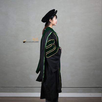 A side view of a person wearing a PhD graduation gown in black with forest green velvet panels, matching sleeve bars, gold trim, and a matching doctoral bonnet with gold tassel.