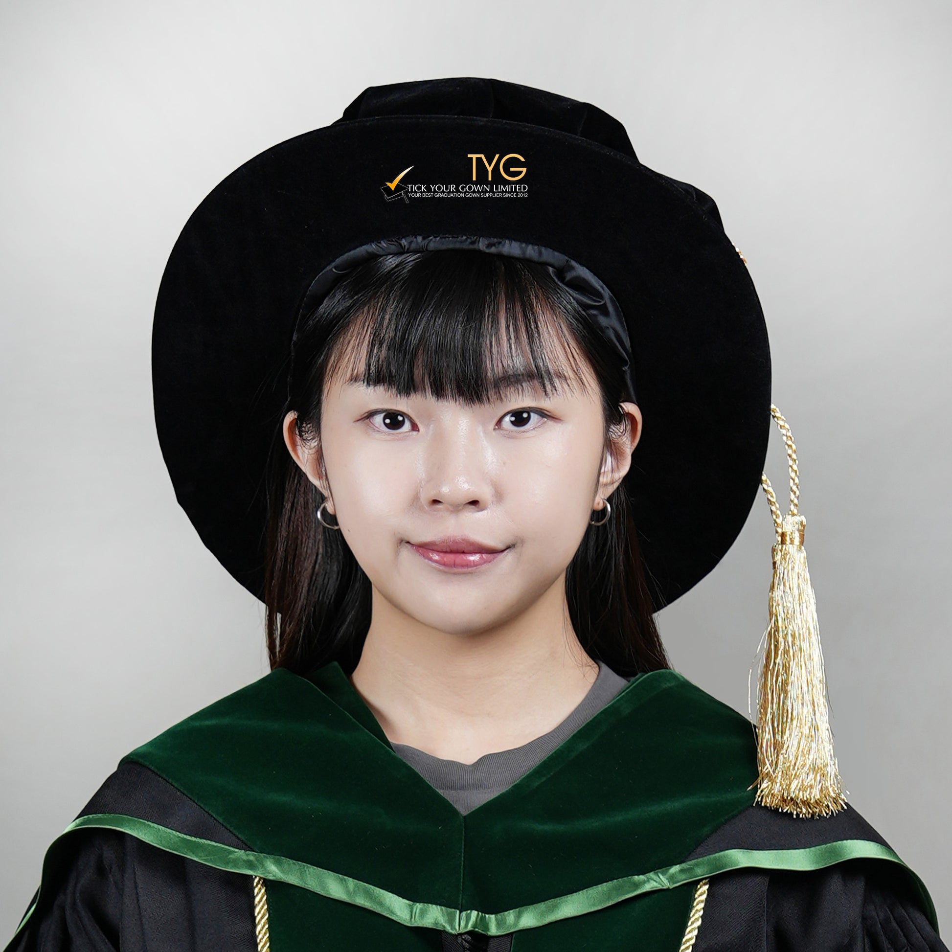A person wearing a graduation gown and doctoral bonnet on a plain background