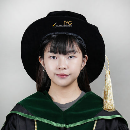 A person wearing a graduation gown and doctoral bonnet on a plain background