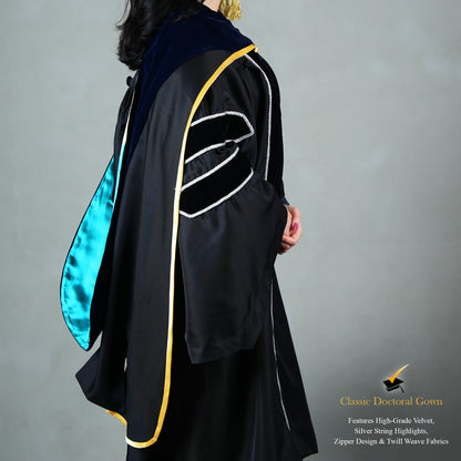 A side view of a person wearing a PhD classic black velvet graduation gown with silver sleeve bars, silver front trim, and a black doctoral bonnet with gold tassel.