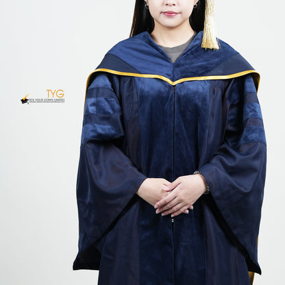A detailed showcase front view of a person wearing a PhD classic navy blue velvet graduation gown with yellow lining hood, and a navy blue doctoral bonnet with gold tassel.