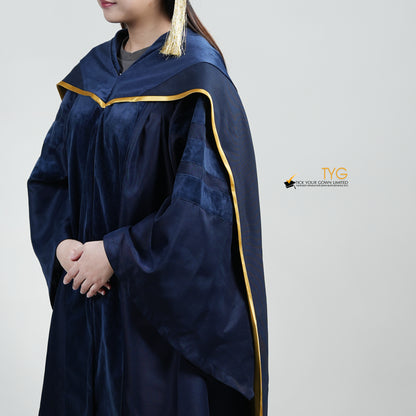 A detailed profile view of a person wearing a PhD classic navy blue velvet graduation gown with yellow lining hood, and a navy blue doctoral bonnet with gold tassel.