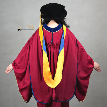 A back view of a person showcasing a premium honorary graduation gown in maroon with royal blue velvet panels, gold trim, and a black doctoral bonnet with gold tassel