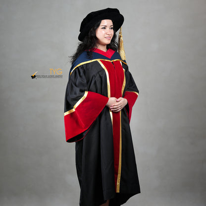 A profile view of a person wearing a premium honorary graduation gown in black with red velvet panels, gold trim, matching red velvet sleeve cuffs, and a doctoral bonnet with gold tassel