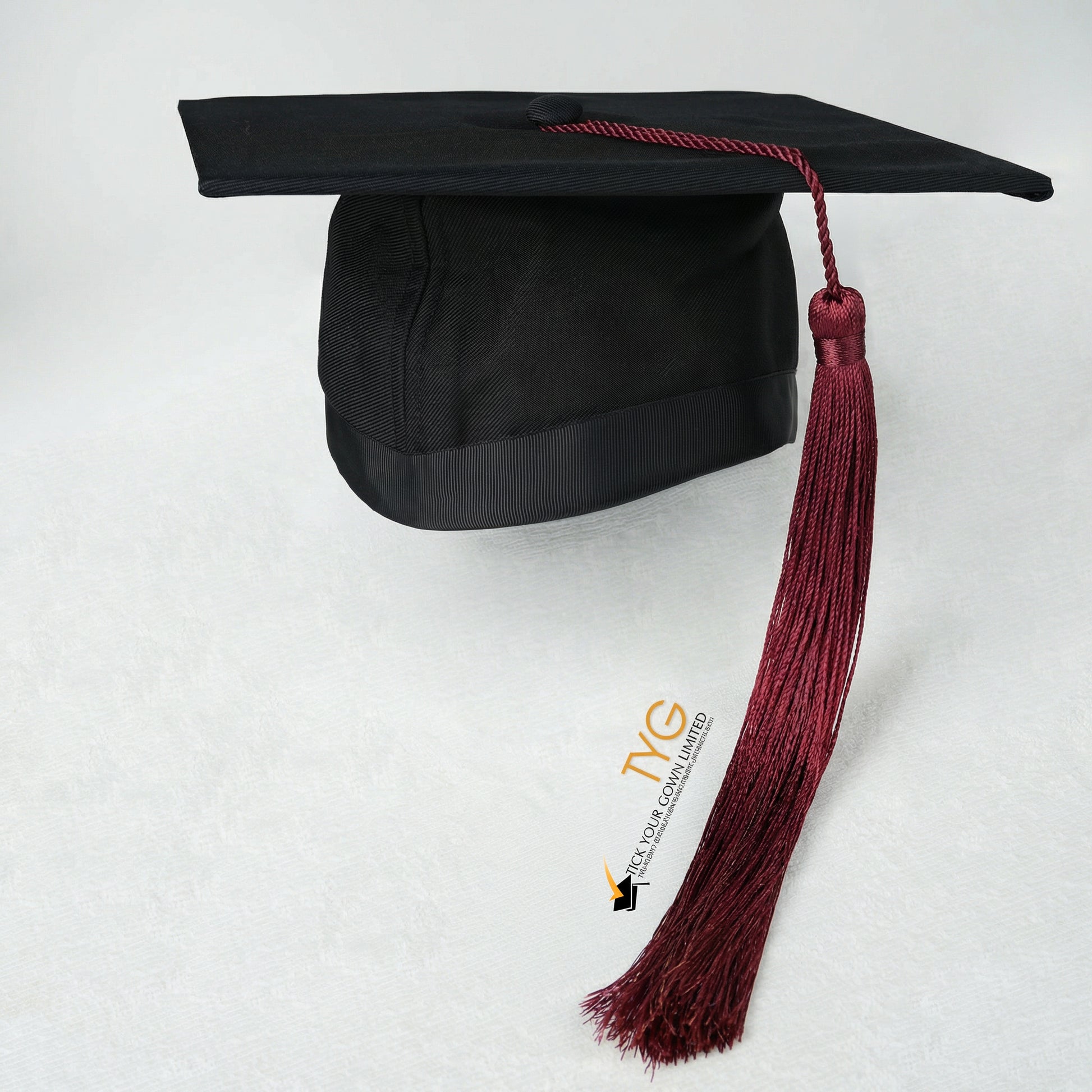 Black graduation cap with maroon tassel on a white background