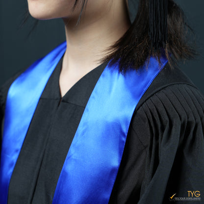 Person wearing a black graduation gown with a blue stole on a dark background
