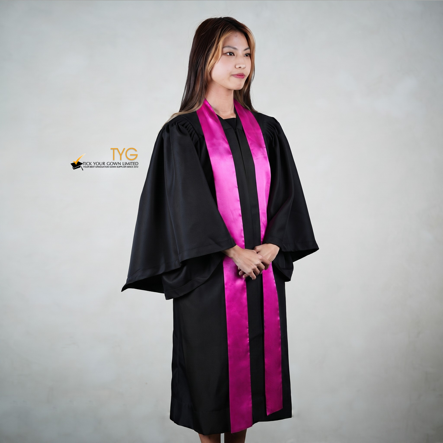 Profile view of a person wearing a black graduation gown with a pink stole on a gray background
