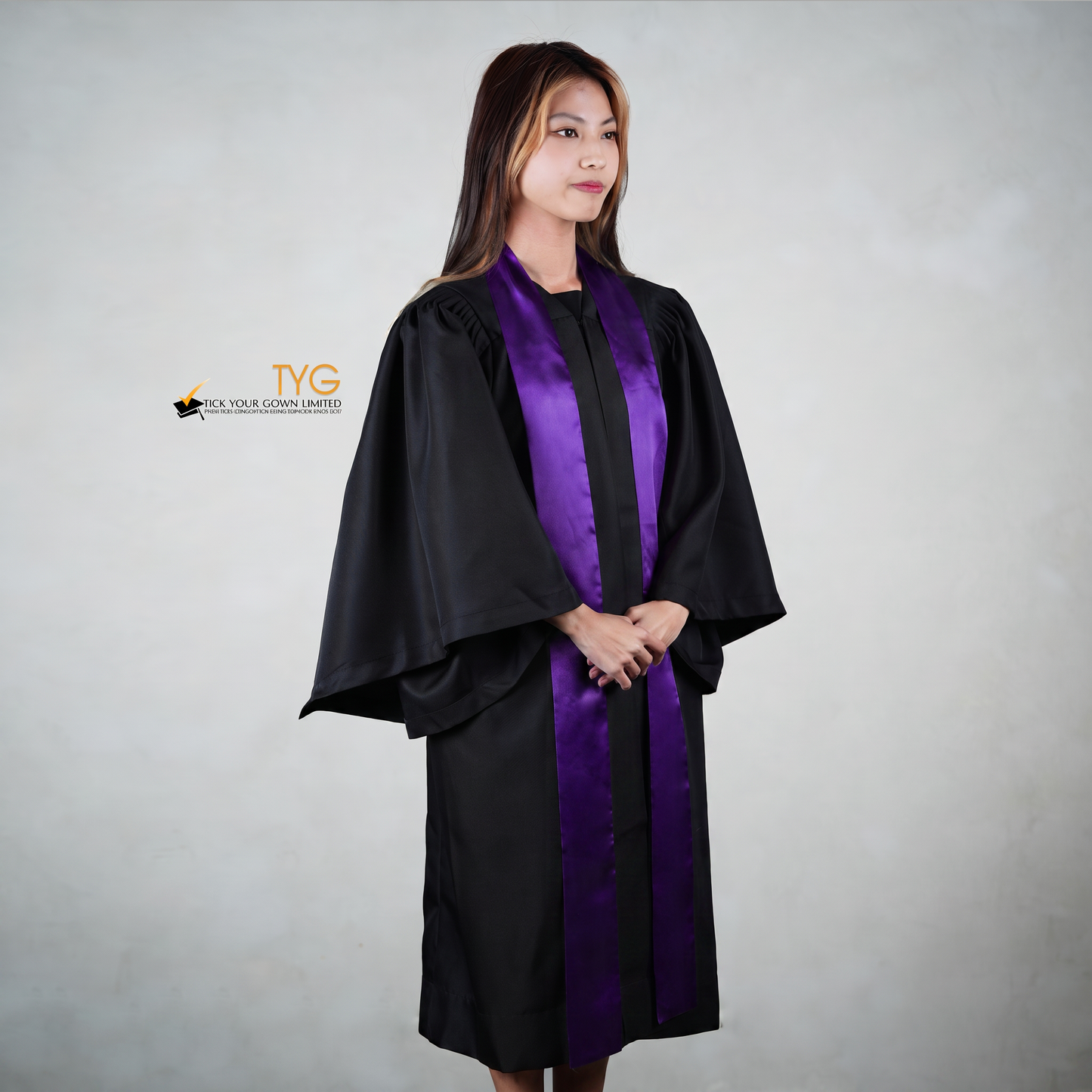 Profile view of a person wearing a black graduation gown with a purple stole on a gray background