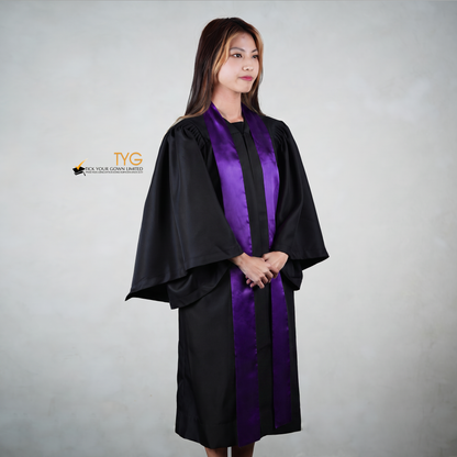 Profile view of a person wearing a black graduation gown with a purple stole on a gray background